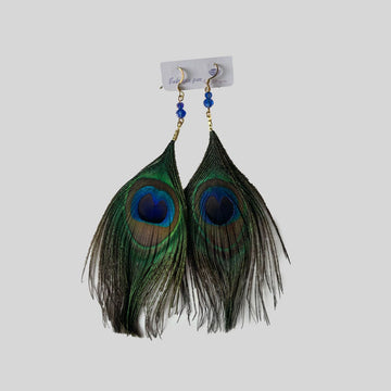 Gros plan des boucles d'oreilles Grandiose montrant la plume de paon et les perles de cristal, détails en acier inoxydable